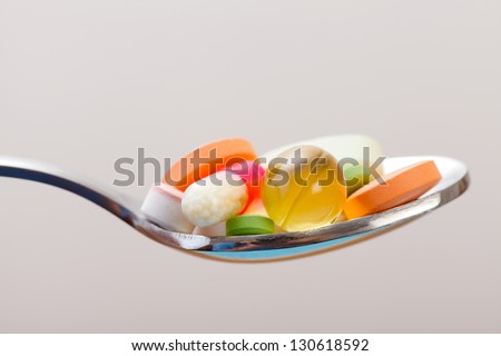 Various drugs vitamins and nutrition supplements on spoon.