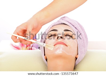 Attractive lady at spa relaxing while receiving facial mask.