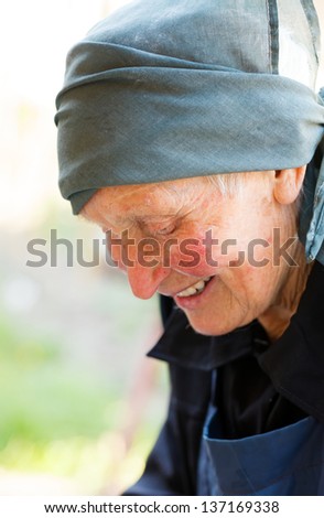 Kind elderly lady in black smiling kindly and looking down.