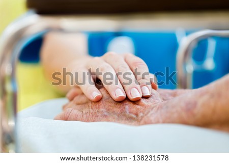 Caring doctor or nurse holding elderly lady's hands in wheelchair Caring doctor or nurse holding elderly lady's hands in wheelchair