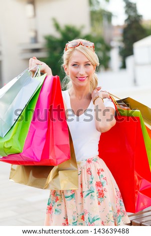 Gorgeous young lady holding shopping bags and smiling.