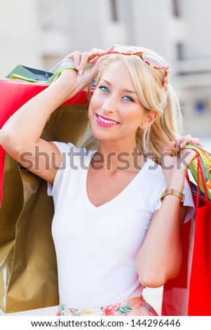 Gorgeous young lady holding shopping bags and smiling.
