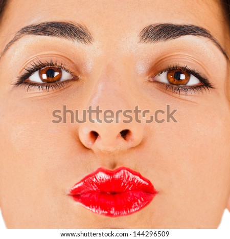 Beautiful brunette woman with red lipstick on sending kisses or making duck face.