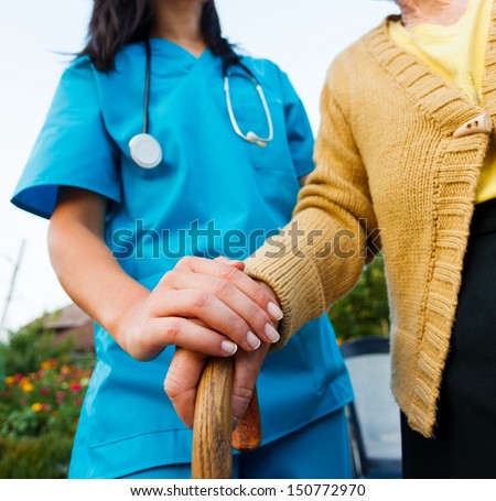 Doctor holding a senior patients \'s hand on a walking stick - special medical care concept for Alzheimer \'s syndrome.