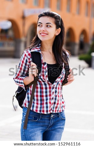 Cute lady with backpack smiling on the street of a city.