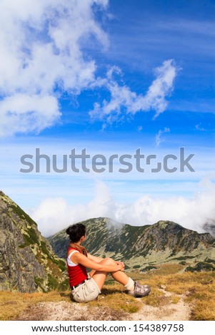 Woman sitting on the top of the moutain looking at the horizon.