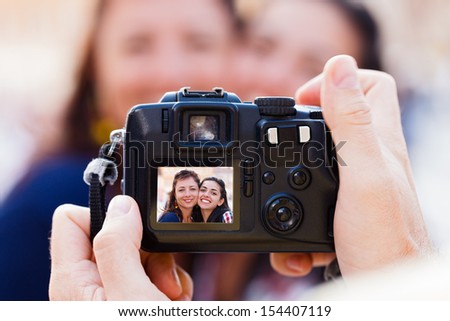 Two beautiful brunette girlfriends being photographed smiling cutely.