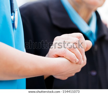 Caring nurse or doctor holding elderly lady\'s hand with care.
