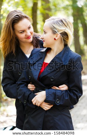 Beautiful fraternal twin sisters glancing at each other while hugging and loving.