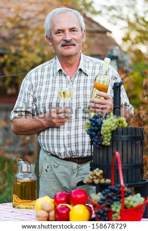 Happy elderly man with wine and harvest crops.
