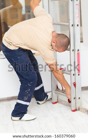 Handyman mounting a step ladder before work.