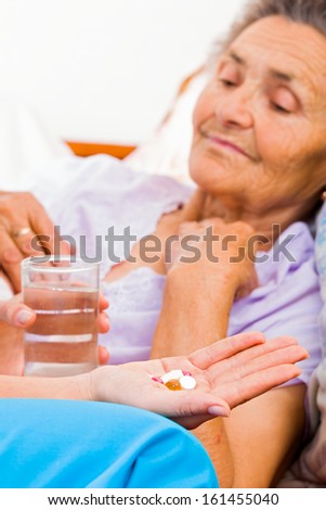 Elderly lady with Alzheimer\'s disease taking pills.