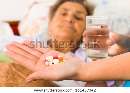 Homecare nurse helping elderly lady to take her daily medicine.