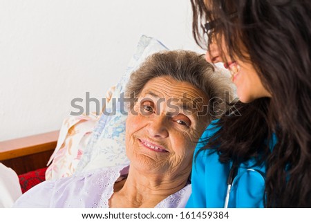 Kind nurse easing elderly lady\'s days in nursing home with care help and joy.