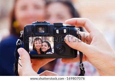 Happy beautiful smiley girlfriends being photographed by a man.