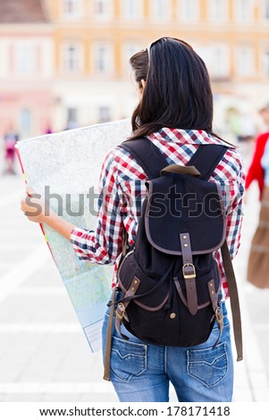Tourist with backpack looking at the map of the city.