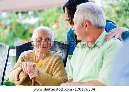 Elderly woman looking to the carer and her son, the visitor.