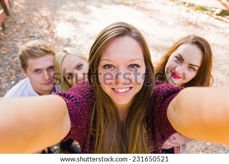 Good friends photobombing a young beautiful woman\'s selfie for social network.