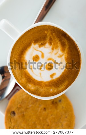 Coffee art on mug drawing on top of the liquid.