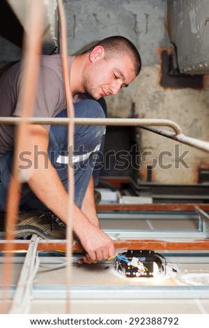 Handy man electrician assembling light working with cables.