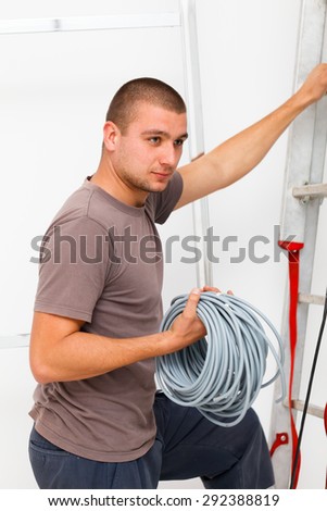 Hard working electrician with cables in hand climbing on ladder.