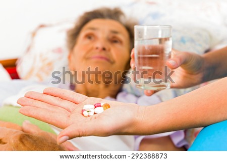 Nurse giving medication to elderly patient in nursing home.