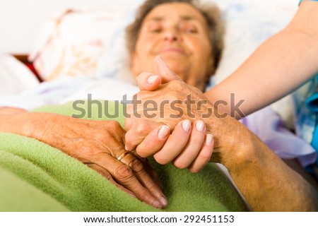 Health care nurse holding elderly lady\'s hand with caring attitude.