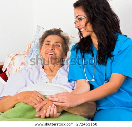 Kind nurse easing elderly lady\'s days in nursing home with care help and joy.