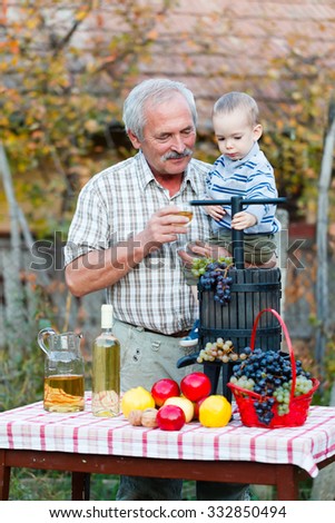 Grandparent holding his grandson in his arms posing with this season \'s rich crops.