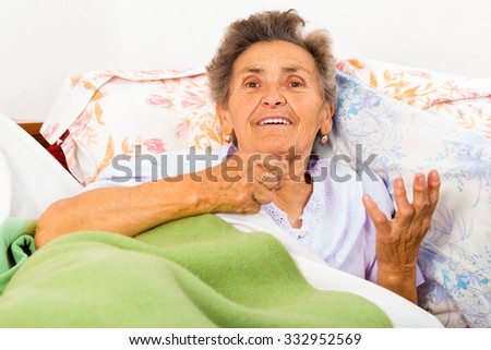Old woman in bed talking and gesturing.