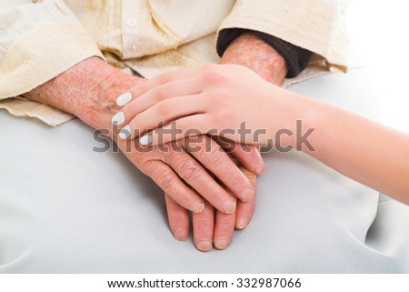 Elderly hands held by a young person - helping concept.