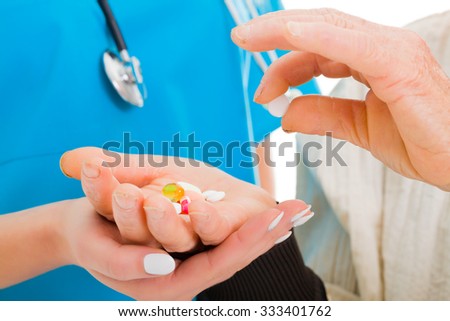 Old woman picking one pill with doctor.