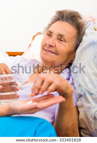 Medication given to elderly woman in bed.