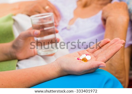 Homecare nurse helping elderly lady to take her daily medicine.