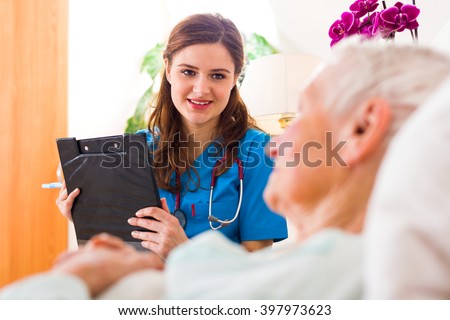 Kind nurse with clipboard in her hands registering senior woman\'s healthcare stats.