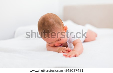 Sad baby crying on bed alone at home.