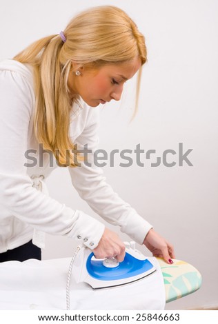 A young woman ironing on an ironing board.