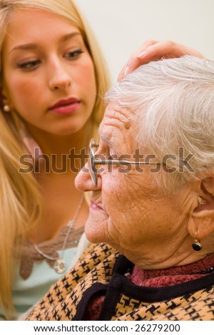 A young woman patting an older one whit trust and empathy (focus on the old woman) - part of a series.