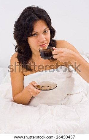 A young woman drinking a cup of coffee at morning, before getting up - part of a series.