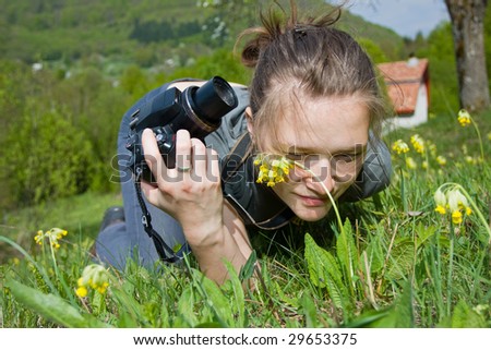 A young woman taking photos whit a compact camera, seeking subject.
