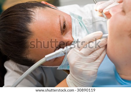 A young dentist working on az elderly woman\'s teeth.