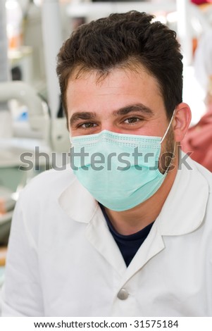 A young male dentist smiling at workplace - part of a series.
