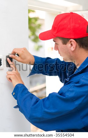 A young electrician installing an electrical switch in a new house.