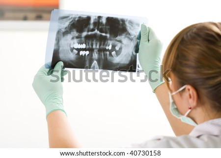 A female dentist examining a panoramic radiography.