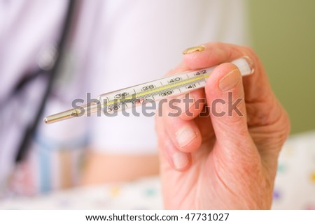 An old woman holding a clinical thermometer in her hand, a blurred image of a doctor with stethoscope in the background.