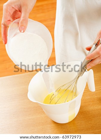 A young cook making dough for muffins ( cupcakes ) - adding sugar.
