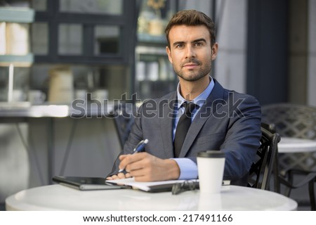 Portrait of young handsome entrepreneur working outside cafe