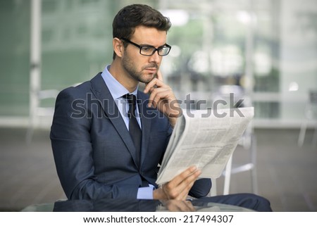 Focused businessman with glasses reading newspaper stock report daily news financial real estate articles