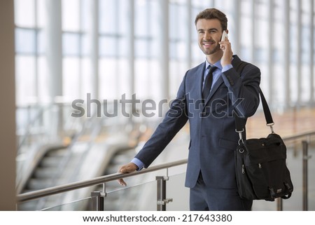 Young smiling businessman calling on the mobile phone at metro station