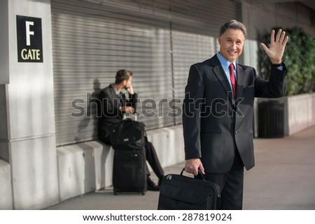 Businessman waves a ride down and says hello departing flight